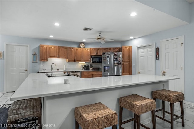 kitchen featuring stainless steel refrigerator with ice dispenser, recessed lighting, light countertops, visible vents, and black microwave