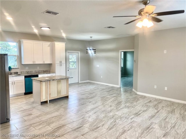 kitchen with dishwashing machine, a kitchen island, ceiling fan, white cabinetry, and hanging light fixtures