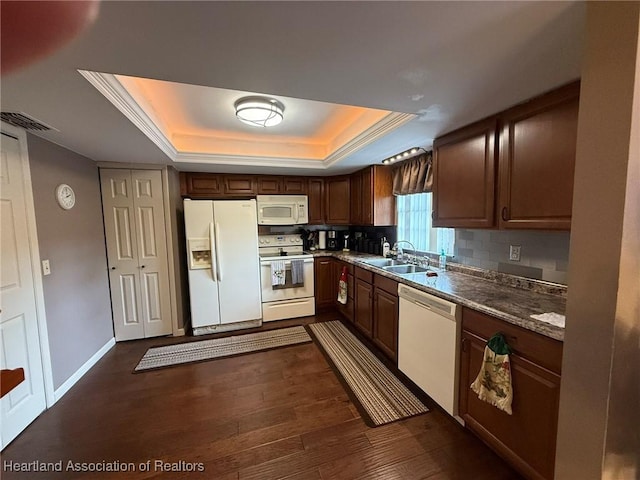 kitchen with white appliances, dark wood-style flooring, a sink, visible vents, and a tray ceiling