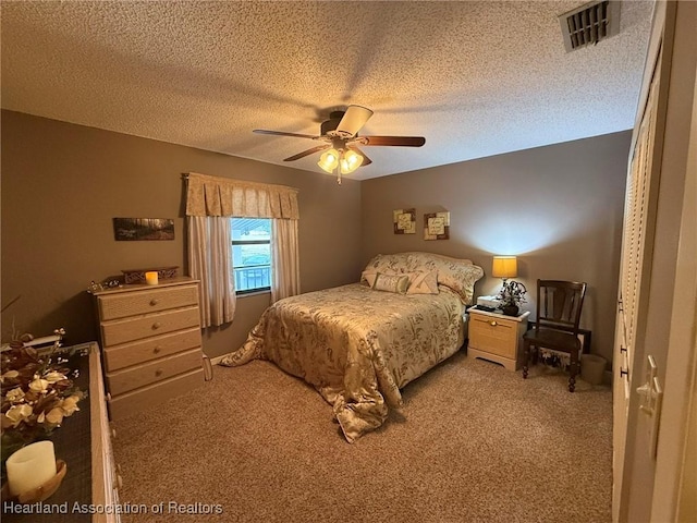 bedroom with a textured ceiling, carpet floors, visible vents, and a ceiling fan