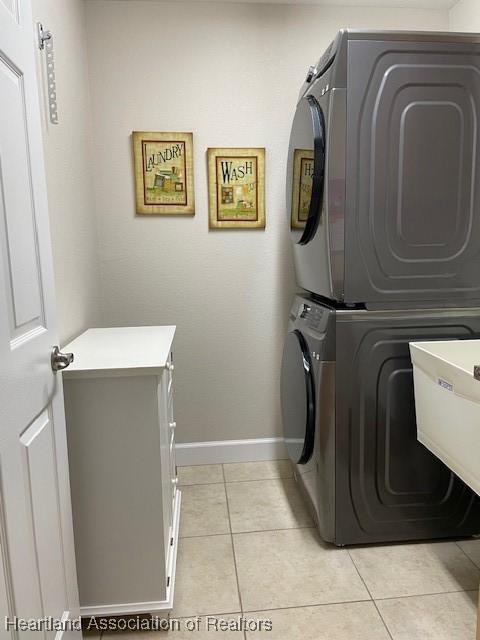 clothes washing area featuring sink, stacked washer and clothes dryer, and light tile patterned flooring