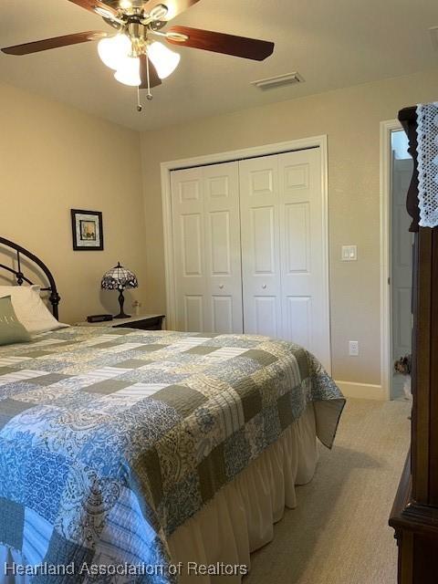 carpeted bedroom featuring ceiling fan and a closet