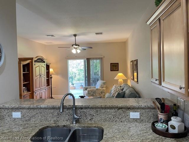 kitchen with light stone countertops, sink, and ceiling fan