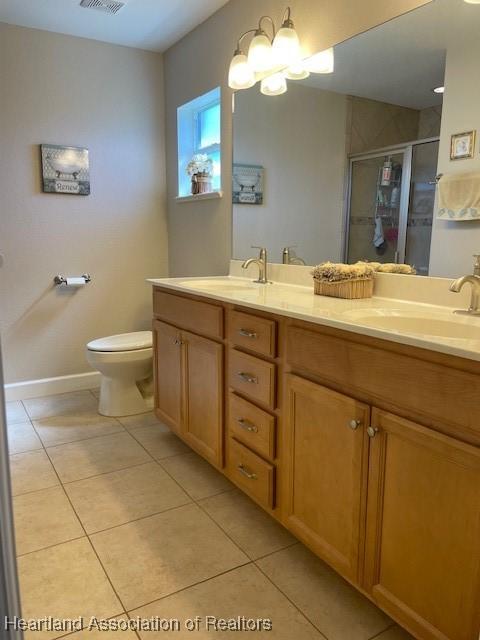 bathroom with toilet, an inviting chandelier, tile patterned floors, an enclosed shower, and vanity