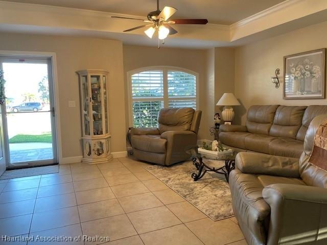 tiled living room with ceiling fan, a healthy amount of sunlight, a tray ceiling, and crown molding