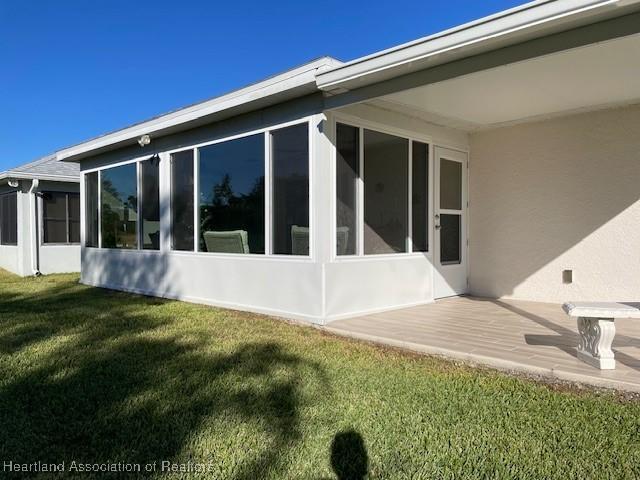 view of side of home with a sunroom and a lawn