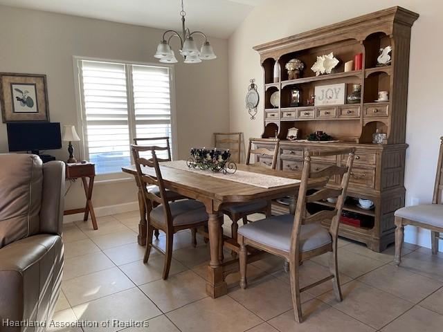 tiled dining area with vaulted ceiling, a wealth of natural light, and a notable chandelier