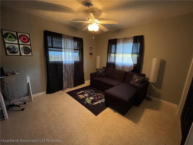 living room with baseboards, visible vents, and ceiling fan