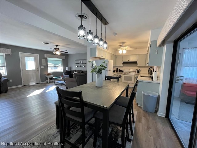 dining room with visible vents, a ceiling fan, baseboards, and wood finished floors