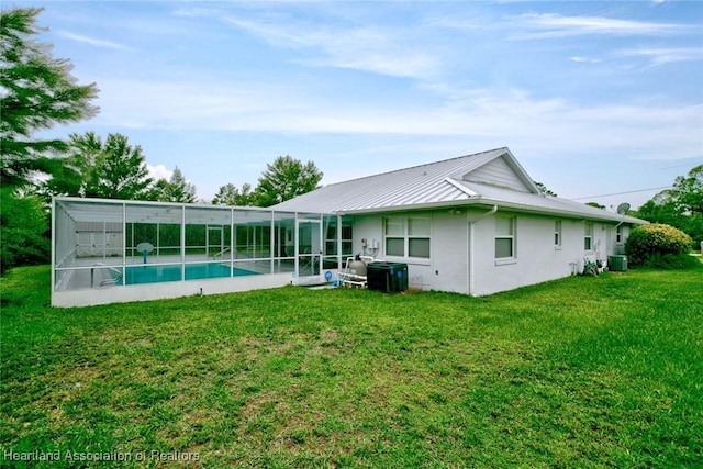 134 Bimini St NE, Lake Placid, FL 33852 - back of house with an outdoor pool, glass enclosure, central AC, a yard, and a standing seam roof