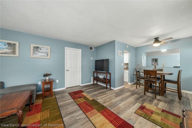 living room featuring hardwood / wood-style floors, a textured ceiling, and ceiling fan