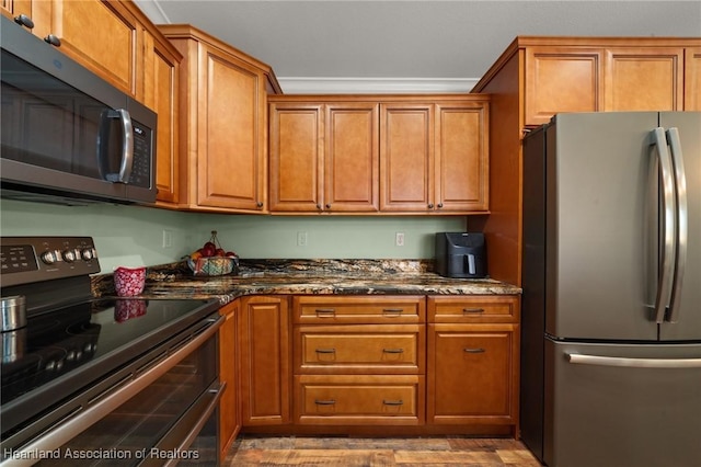 kitchen with dark stone countertops, crown molding, and appliances with stainless steel finishes