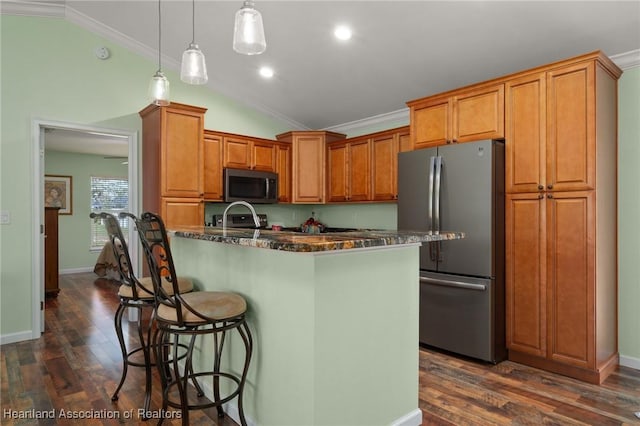 kitchen with a center island with sink, pendant lighting, a kitchen bar, and stainless steel appliances