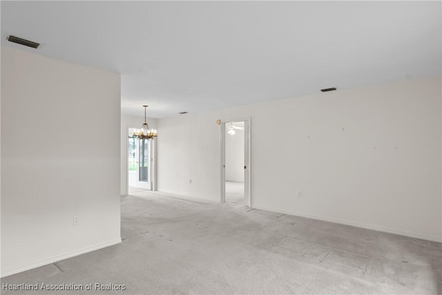 unfurnished room featuring an inviting chandelier and light colored carpet