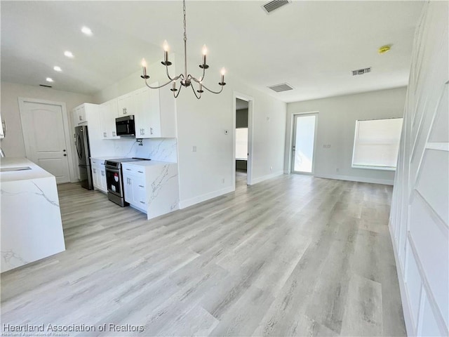 1256 Washington Blvd NE, Lake Placid, FL 33852 - kitchen featuring stainless steel range with electric cooktop, a chandelier, freestanding refrigerator, white cabinetry, and light wood-type flooring