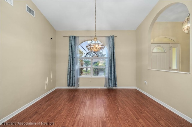 spare room featuring hardwood / wood-style floors and a notable chandelier