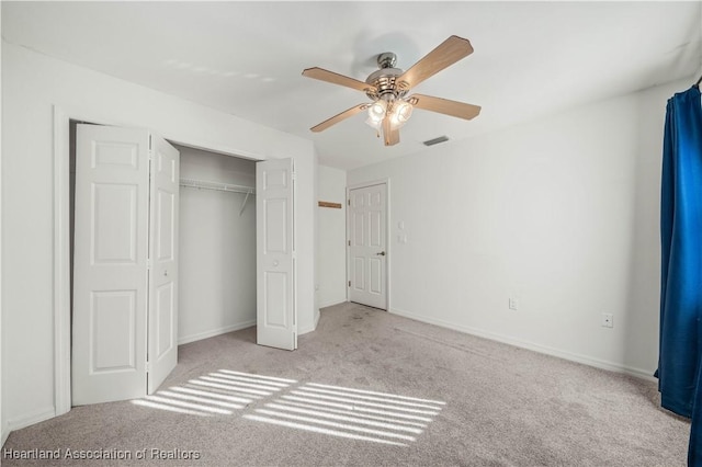 unfurnished bedroom with ceiling fan, a closet, and light carpet