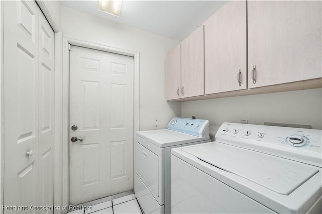 laundry room with light tile patterned flooring, cabinets, and washing machine and dryer