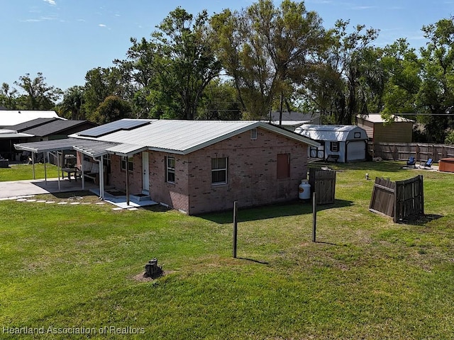 view of home's exterior with a storage shed, solar panels, a patio, an outdoor structure, and brick siding