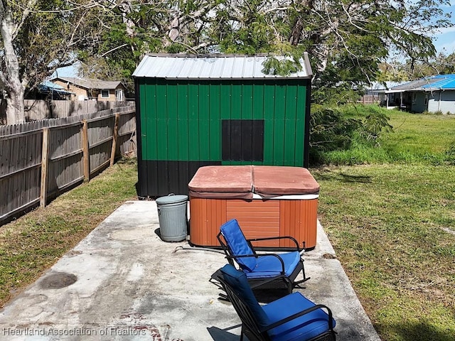 view of patio with a storage shed, a hot tub, fence, and an outbuilding