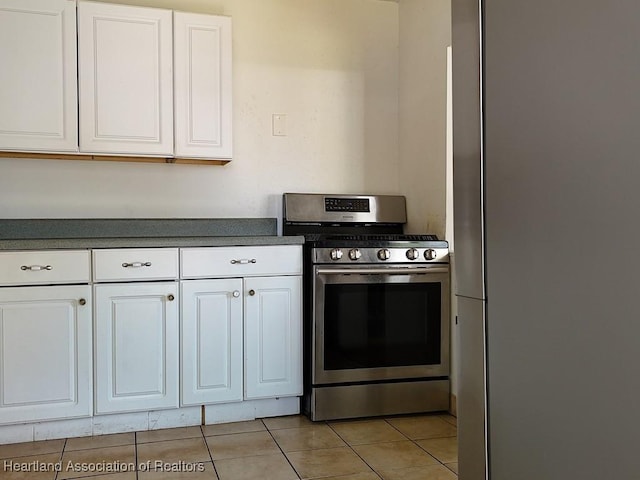 kitchen with light tile patterned floors, stainless steel appliances, dark countertops, and white cabinets