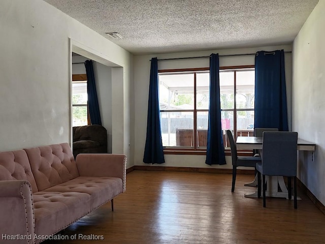 interior space with visible vents, a textured ceiling, baseboards, and wood finished floors