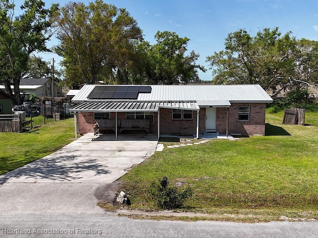 ranch-style home with metal roof, brick siding, a front yard, and aphalt driveway