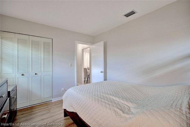 bedroom with light hardwood / wood-style floors and a closet