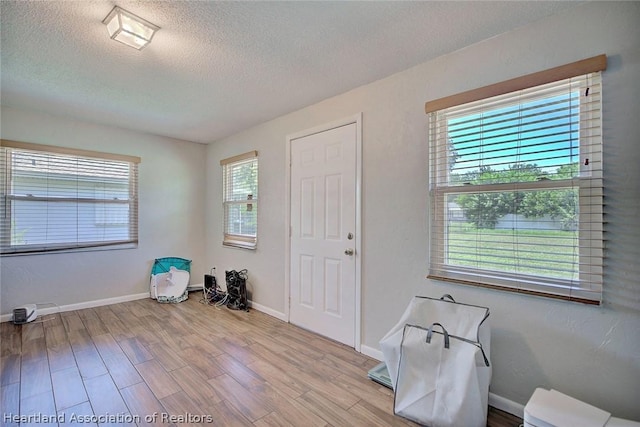 foyer entrance with a textured ceiling and light wood-type flooring