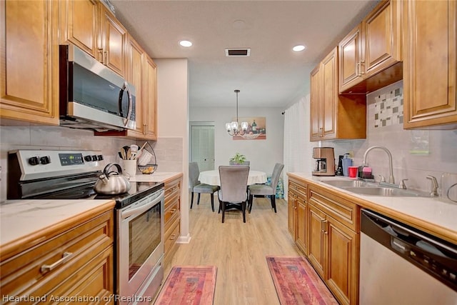 kitchen with sink, light hardwood / wood-style flooring, a notable chandelier, pendant lighting, and appliances with stainless steel finishes