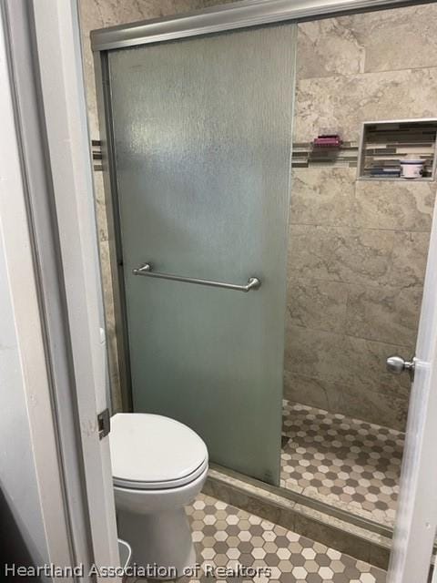 bathroom featuring tile patterned floors, toilet, and walk in shower