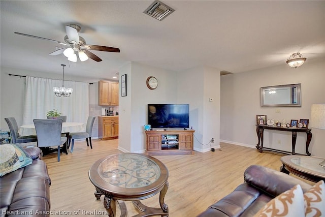 living room featuring ceiling fan with notable chandelier and light wood-type flooring