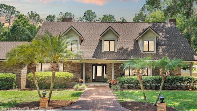 cape cod house featuring a yard