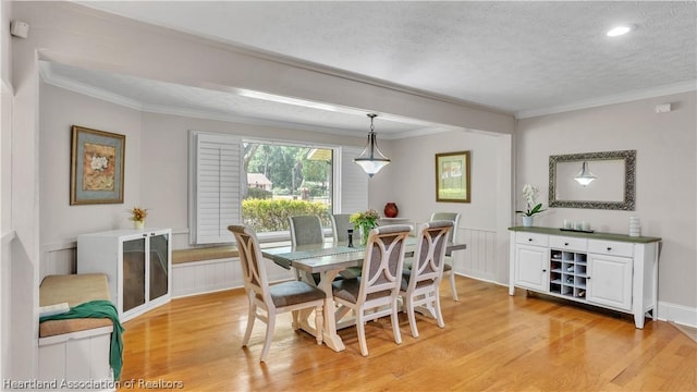 dining room with crown molding, light wood-type flooring, and a textured ceiling