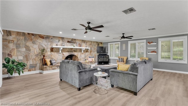 living room featuring a wealth of natural light, a fireplace, light hardwood / wood-style floors, and ornamental molding