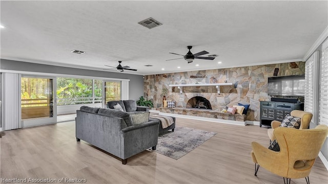 living room featuring crown molding, light hardwood / wood-style flooring, ceiling fan, a textured ceiling, and a fireplace