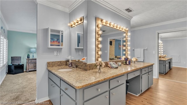 bathroom featuring hardwood / wood-style floors, vanity, crown molding, and a textured ceiling