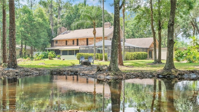 back of house with a lanai, a yard, and a water view