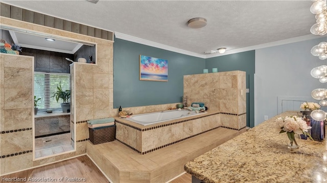 bathroom featuring a textured ceiling, a relaxing tiled tub, hardwood / wood-style flooring, and ornamental molding