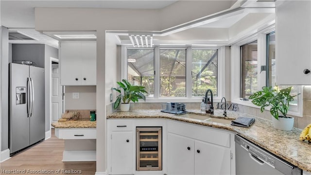 kitchen with wine cooler, white cabinetry, sink, and appliances with stainless steel finishes