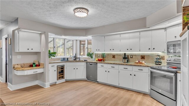 kitchen with white cabinetry, beverage cooler, light hardwood / wood-style flooring, a textured ceiling, and appliances with stainless steel finishes