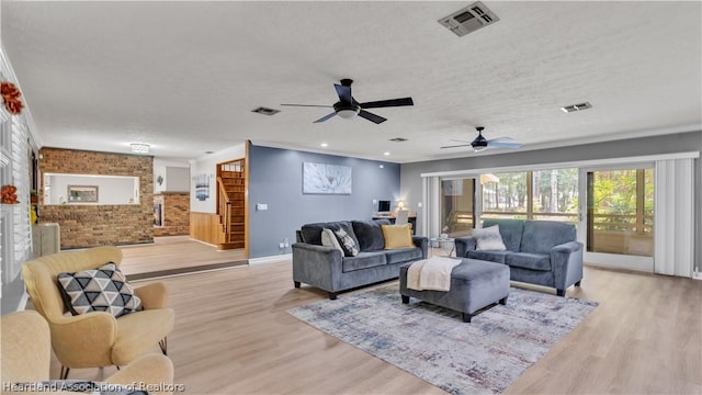 living room featuring ceiling fan, light wood-type flooring, and a textured ceiling