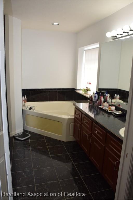 bathroom with tile patterned flooring, vanity, and a bath