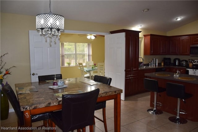 dining room with light tile patterned floors, vaulted ceiling, and ceiling fan with notable chandelier