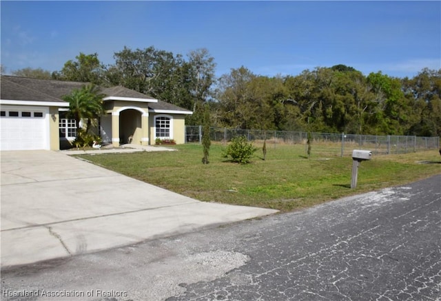 view of front of house with stucco siding, concrete driveway, a front yard, fence, and a garage