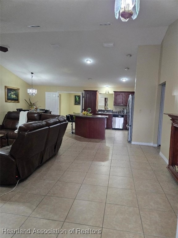 living room with light tile patterned floors, vaulted ceiling, visible vents, and baseboards