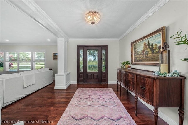 foyer with dark wood-type flooring, crown molding, and decorative columns