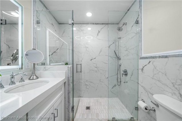 bathroom with vanity, toilet, an enclosed shower, and tile walls