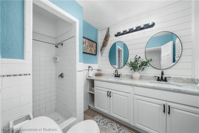 bathroom featuring a tile shower, vanity, and toilet