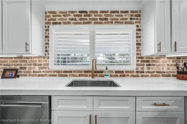 kitchen featuring dishwasher, white cabinetry, sink, and brick wall